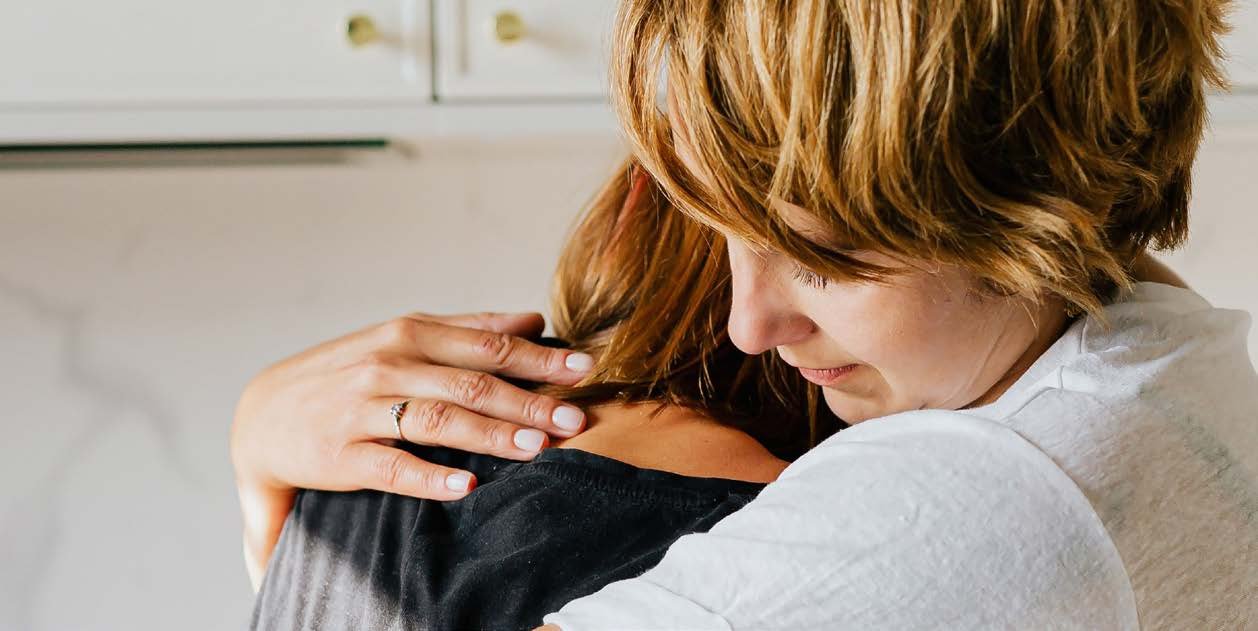 Eine Frau mit kurzen blonden Haaren nimmt eine Person tr&ouml;stend in den Arm.