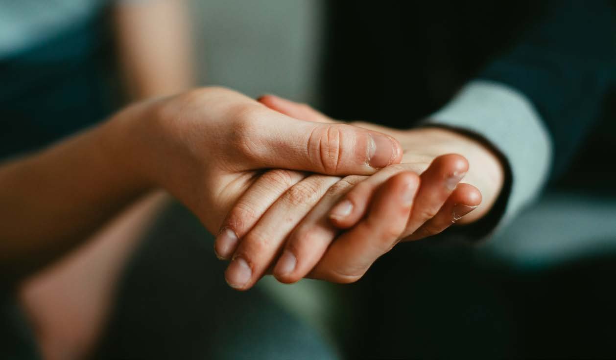 Nahaufnahme: Eine Hand h&auml;lt unterst&uuml;tzend die Hand einer anderen Person.